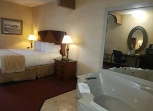 - une chambre d'hôtel avec un lit et une baignoire dans l'établissement Victory Suites, à Warren