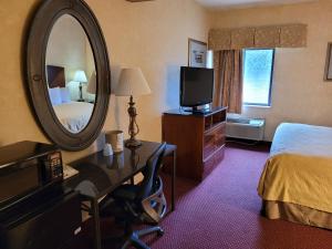 Habitación de hotel con cama y espejo en Victory Suites, en Warren