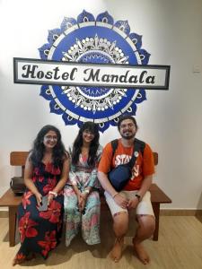 a group of three people sitting under a sign at Hostel Mandala in Anjuna