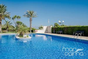 a swimming pool with blue water and palm trees at Apto. Bellavista by MarCalma in Miami Platja