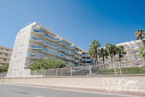a tall white building with palm trees in front of it at Apto. Bellavista by MarCalma in Miami Platja