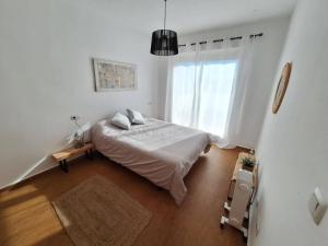 a white bedroom with a bed and a window at Ático de Laura in Armilla