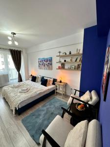 a bedroom with a bed and a couch and a blue wall at Q Apartament Palas Mall in Iaşi