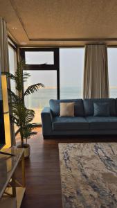 a living room with a blue couch and a palm tree at sea breeze RAK in Ras al Khaimah