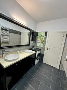 La salle de bains est pourvue de 2 lavabos et d'un lave-linge. dans l'établissement Q Apartament Palas Mall, à Iaşi