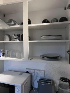 a kitchen with white shelves with plates and dishes at Luxury Room on Park Road Close to University & QMC Hospital in Nottingham +6 photos