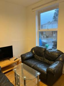 a living room with a leather couch and a window at 36 park road house in Nottingham