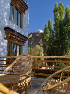 two wooden chairs and a table on a balcony at Rock Castle Residency in Leh