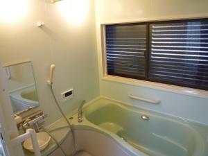 baño con bañera, aseo y ventana en ゲストハウス あずも GuestHouse AZMO en Matsue