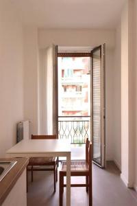 cocina con mesa, sillas y ventana en Appartamento Lorenteggio - Piazza Frattini affaccio interno, 2 balconi, en Milán