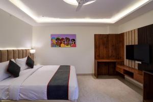 um quarto com uma cama e uma televisão de ecrã plano em OYO Collection O Hotel Sg Inn em Greater Noida