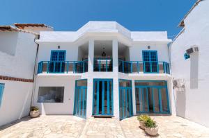 una grande casa bianca con porte e finestre blu di Pousada Mar de Geribá a Búzios
