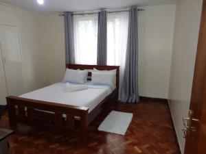 a bedroom with a bed and a window with curtains at Amani guest house in Nairobi
