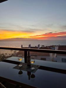 聖地亞哥港的住宿－Bahia de Santiago，两杯葡萄酒坐在桌子上,享有海景