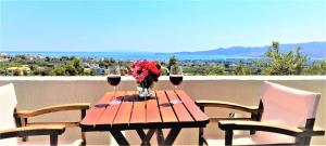 einen Holztisch mit Weingläsern und Blumen auf dem Balkon in der Unterkunft Aspra Chomata Villas in Karystos