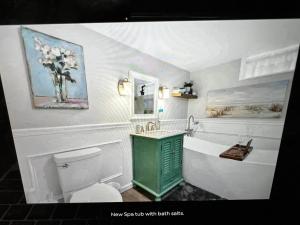 a bathroom with a toilet and a vase of flowers on the wall at Sunset Cove in East Hampton +47 photos