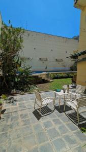 a patio with two chairs and a table and a wall at Rodex Casa Boutique - Paraíso céntrico con pileta, terraza, asador in San Miguel de Tucumán