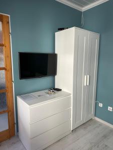 un armario blanco con TV en una pared azul en Andrea Apartman, en Bük