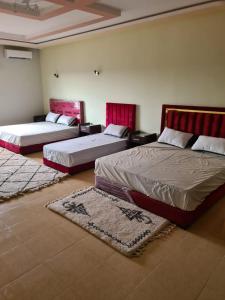 two beds in a room with two rugs at Maison d’hôtes SOUIHLA in Oulad Sidi Cheïkh