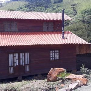 烏魯比西的住宿－Sítio Fundo Da Grota，一座木房子,有红色的屋顶和岩石