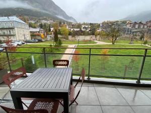 a table and chairs on a balcony with a view at Appartement proche des pistes Serre Chevalier in Briançon
