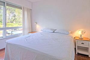 uma cama branca num quarto com uma janela em Oceana Suites en Bora Bora, con vistas a la ciudad em Punta del Este