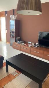 ein Wohnzimmer mit einem TV und einem schwarzen Tisch in der Unterkunft Adosado con increíbles vistas a 150m de la playa in Moaña