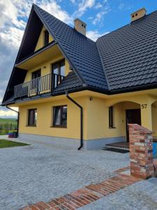 een geel huis met een zwart dak bij Dom na Ubocy in Groń