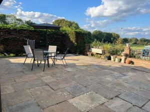 une terrasse avec une table, des chaises et un parasol dans l'établissement I bedroom flat on a gated farm in Tadworth, à Purley