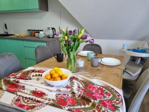 een tafel met een kom sinaasappels en een vaas met bloemen bij Dom na Ubocy in Groń