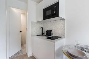 a white kitchen with a sink and a microwave at Résidence Saint Charles - Parc des Expositions in Paris