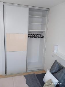 a closet with a glass door next to a bed at Zoé Apartman Debrecen Nagyerdő in Debrecen