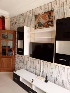 uma sala de estar com uma televisão e uma parede em Appartement meublé liberté 6 em Dakar