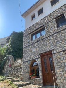 un edificio de piedra con puerta de madera y pared de piedra en Οικία αποζαρι μικρή περσα, en Kastoria