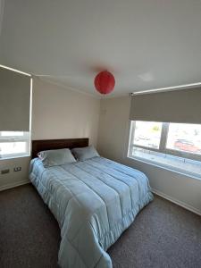 1 dormitorio con 1 cama grande y luz roja en Departamento Amoblado Centro Factura Empresas, en Concepción