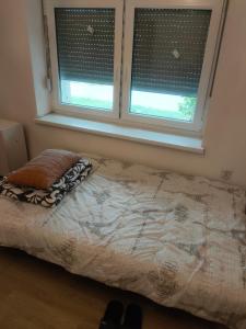 a bedroom with a bed and two windows with blinds at Warm and comfortable apartment in Subotica