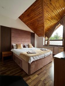 Un dormitorio con una cama grande con techo de madera. en Infinity Villa, en Buşteni