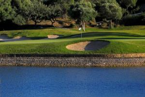 Blick auf einen Golfplatz mit einer Wasserfläche in der Unterkunft Small Oasis Nelson Mandela Apartment with sea view, two bedrooms, parking, terrace and pool in Manilva