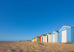a row of beach houses on a sandy beach at London Cottage in Halesworth