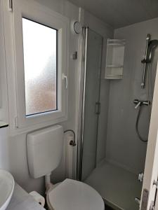 a bathroom with a toilet and a shower with a window at Bajki Mobile home in Biograd na Moru