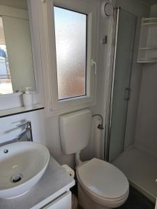 a bathroom with a sink and a toilet and a window at Bajki Mobile home in Biograd na Moru