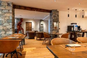 a restaurant with tables and chairs and a stone wall at Raccard Resort de Montagne in Torgnon