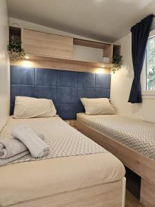 two beds in a small bedroom with a blue headboard at Bajki Mobile home in Biograd na Moru