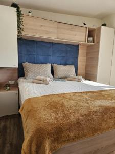 a bedroom with a large bed with a blue headboard at Bajki Mobile home in Biograd na Moru