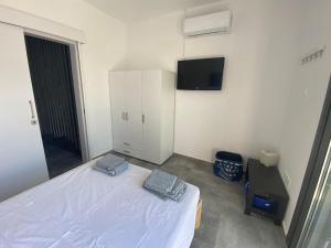 a bedroom with a bed and a tv on the wall at Green Bay Area Apartment in Protaras