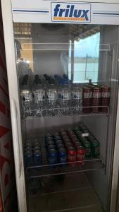 a refrigerator filled with drinks and cans of soda at Canto do lago pousada in Guapé