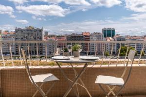 a table and chairs on a balcony with a view of a city at NEW - Luxury & bright apartment Lisbon in Lisbon