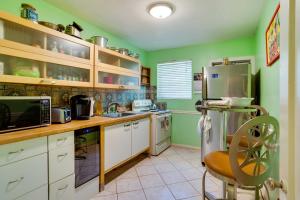 cocina con paredes verdes y armarios blancos en West Palm Beach Home with Fenced-In Yard and Deck! en West Palm Beach