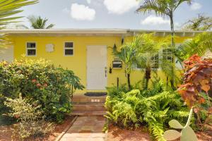 a yellow house with a white door and some plants at West Palm Beach Home with Fenced-In Yard and Deck! in West Palm Beach