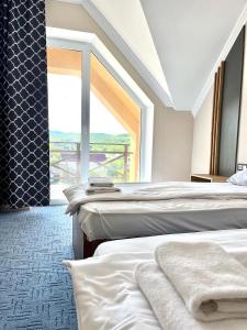 dwa łóżka w pokoju z dużym oknem w obiekcie RIVER SIDE w mieście Polyana (Polana)